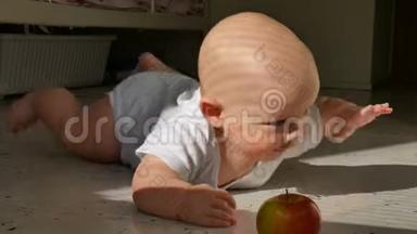 六个月大的婴儿躺在地板上，<strong>伸手要</strong>一个红苹果。 婴儿学会爬行。 孩子累了，把头